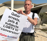 Peter Tatchell holds up a sign protesting against Qatar's anti-LGBTQ+ regime