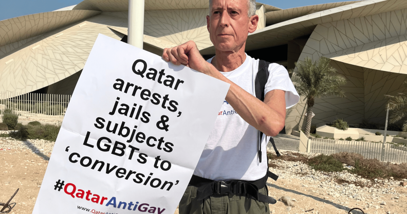 Peter Tatchell holds up a sign protesting against Qatar's anti-LGBTQ+ regime