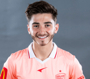 Josh Cavallo smiles as he wears a pink football uniform for the Australian team Adelaide United