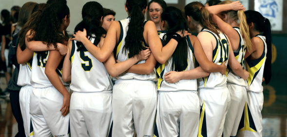 A team of young people gather together in a huddle while playing sports