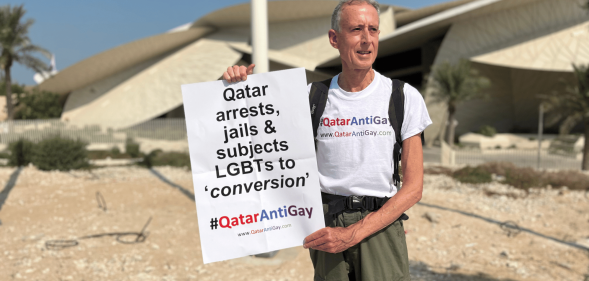 A photo of Peter Tatchell in Qatar holding his LGBTQ+ placard during his protest