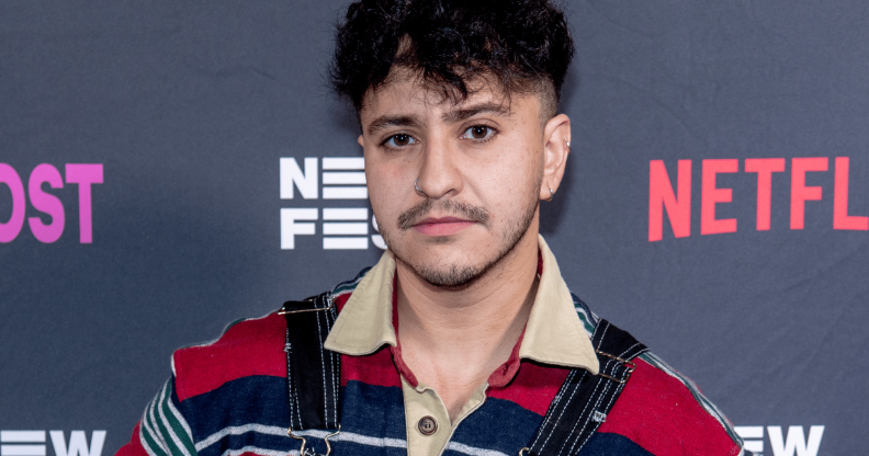 Zach Barack wears a striped shirt as he stands in front of a background with the Netflix logo on it