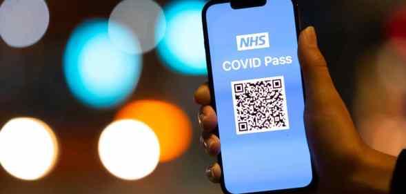 A woman holds an Apple iPhone showing a NHS Covid Pass on October 8, 2021.