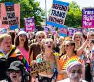 A large group of people holding pro-trans signs march through London during a Trans+ Pride march