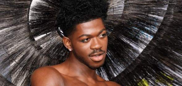 Lil Nas X wears a feathered headpiece as he poses for a photo