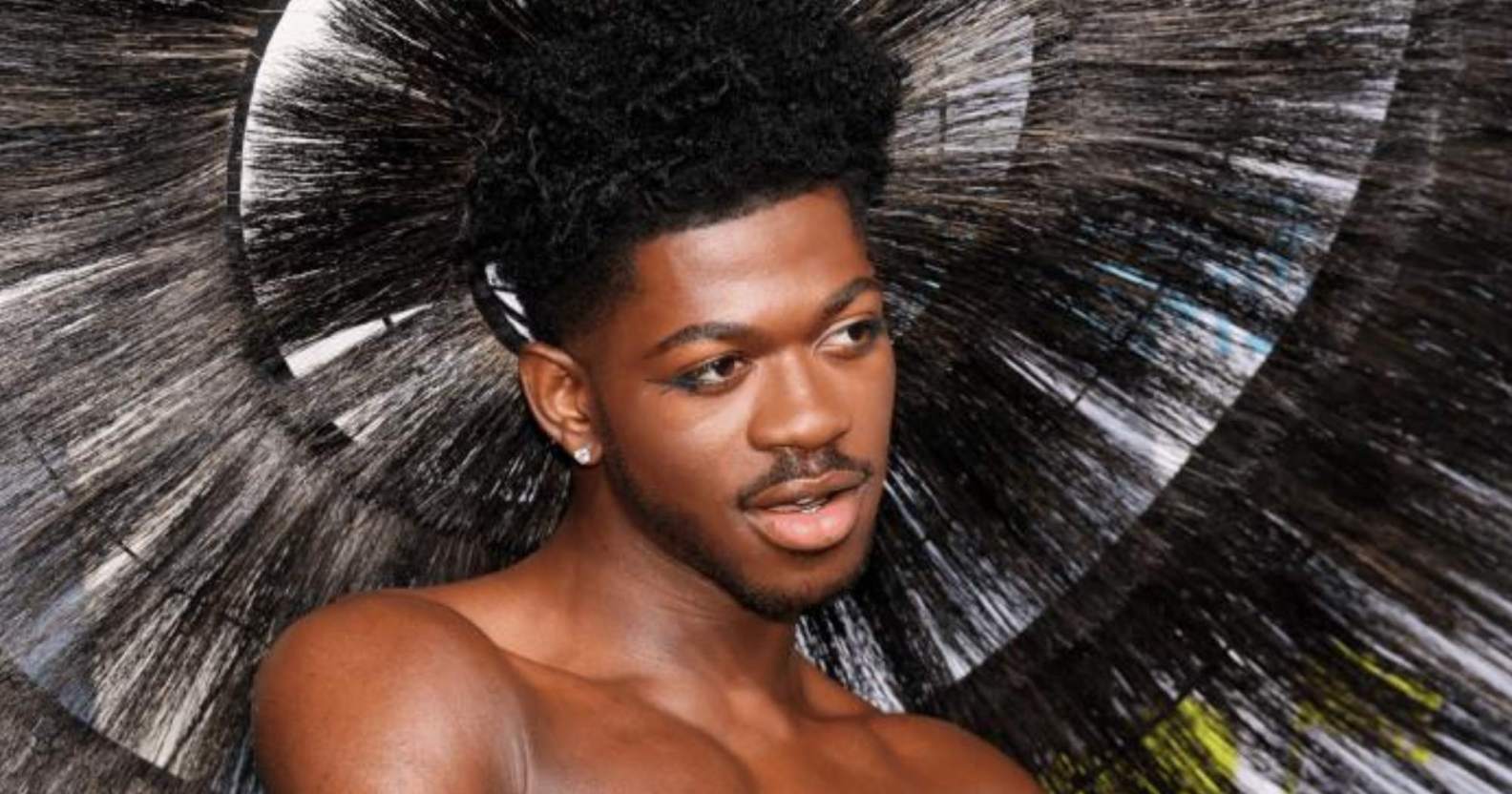 Lil Nas X wears a feathered headpiece as he poses for a photo