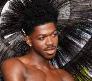Lil Nas X wears a feathered headpiece as he poses for a photo