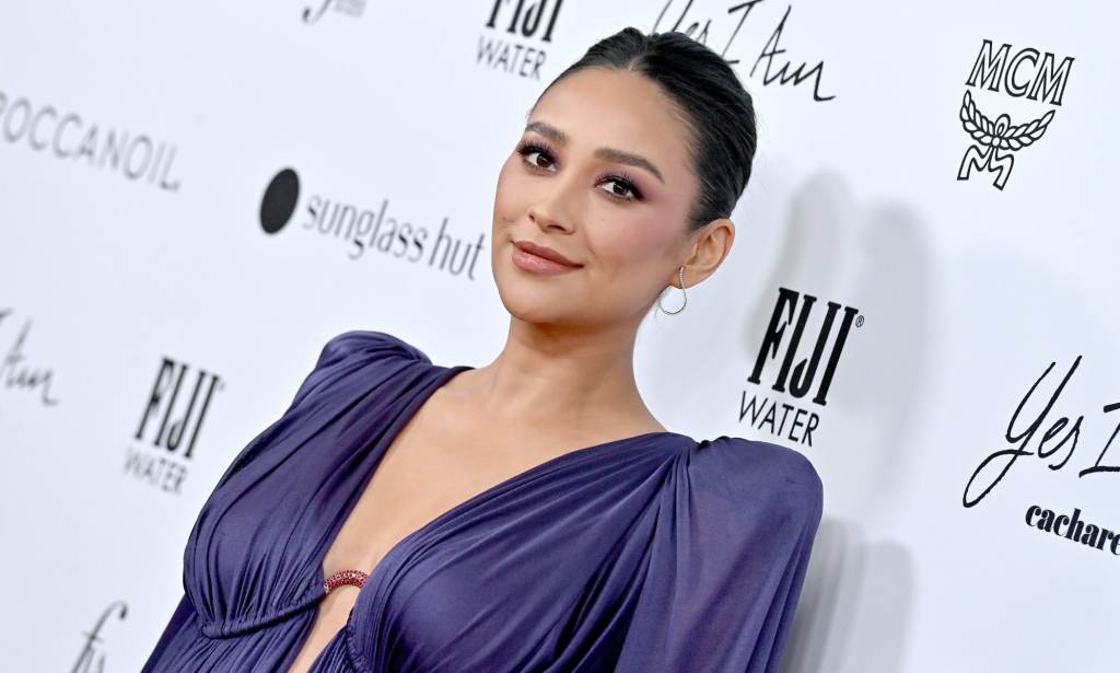 A photo of actor Shay Mitchell wearing a purple dress at a media event