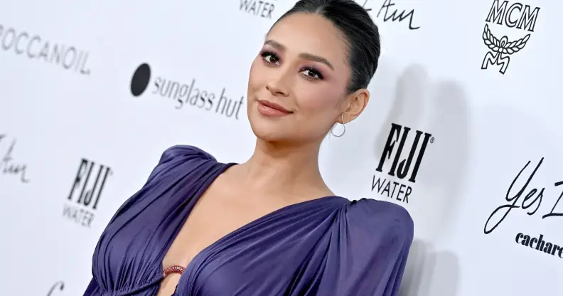 A photo of actor Shay Mitchell wearing a purple dress at a media event