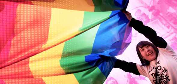 A person holding up the LGBTQ Pride flag