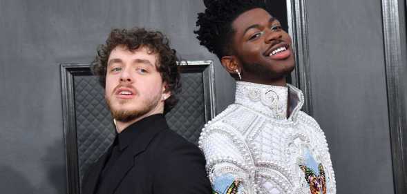 Jack Harlow wears a black outfit as he stands back-to-back with Lil Nas X, who is wearing a white outfit with detailed embroidery