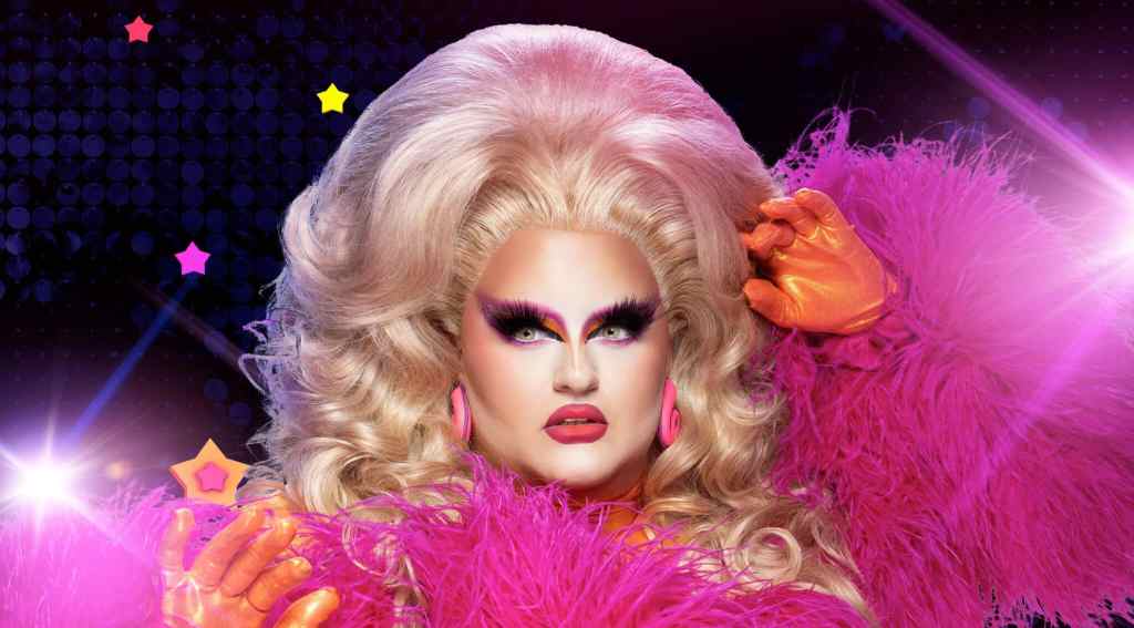A promotional photo of Victoria Scone in full pink drag outfit with spotlight graphics shining in the background