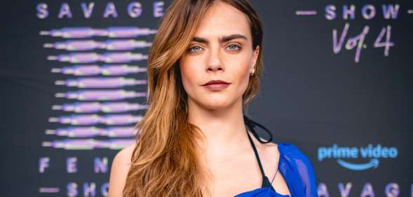 Cara Delevingne in a blue top, centre of the camera looking forward.