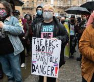 A person holds up a sign reading 'The BBC's bigotry is putting trans folk in danger'