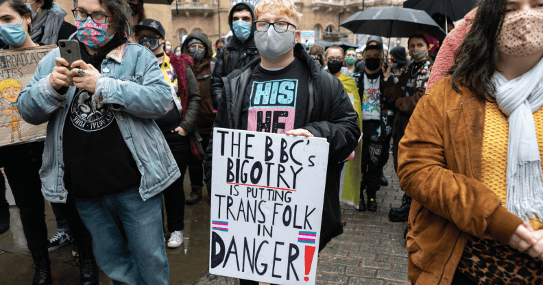 A person holds up a sign reading 'The BBC's bigotry is putting trans folk in danger'