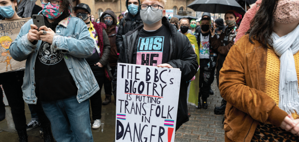 A person holds up a sign reading 'The BBC's bigotry is putting trans folk in danger'