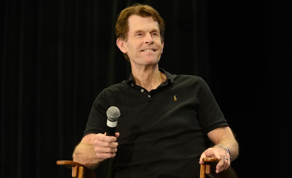 Kevin Conroy holds a microphone on stage