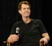 Kevin Conroy holds a microphone on stage