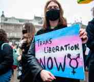 A trans protester holds a placard saying trans liberation now during a demonstration