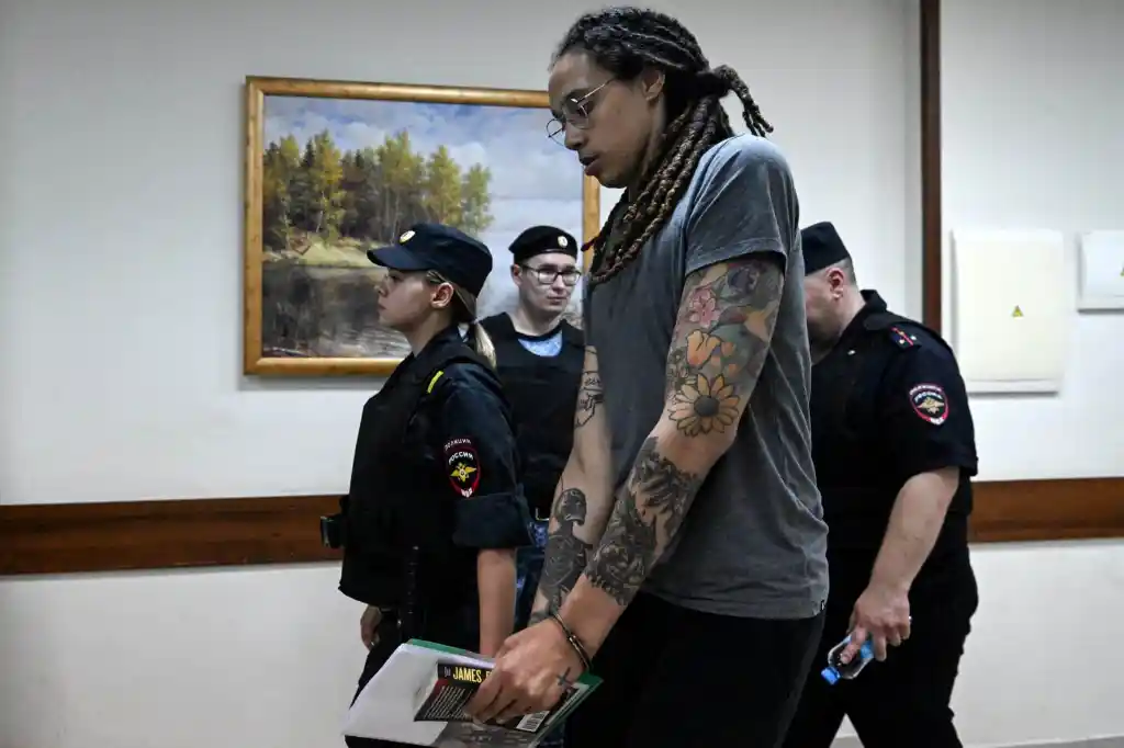 Brittney Griner is brought from a Russian court room surrounded by armed guards.