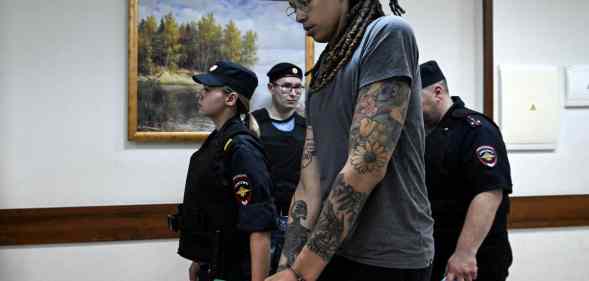 Brittney Griner is brought from a Russian court room surrounded by armed guards.