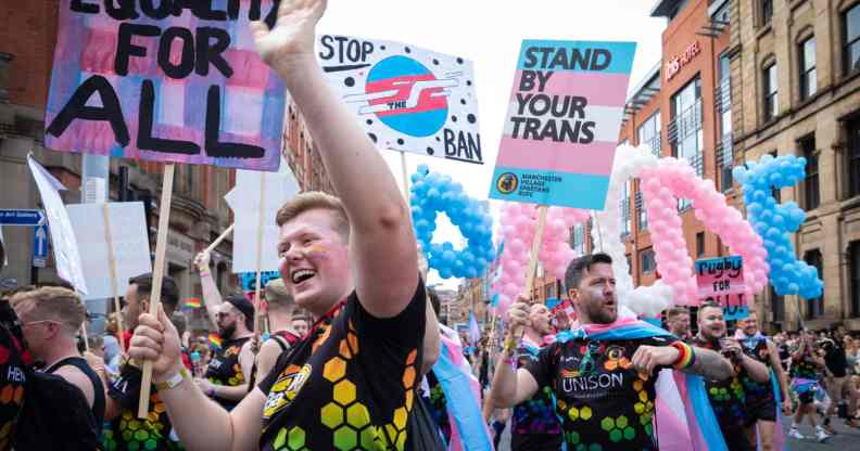 Picture showing people holding pro-trans placards as they march at a trans Pride parade in Manchester