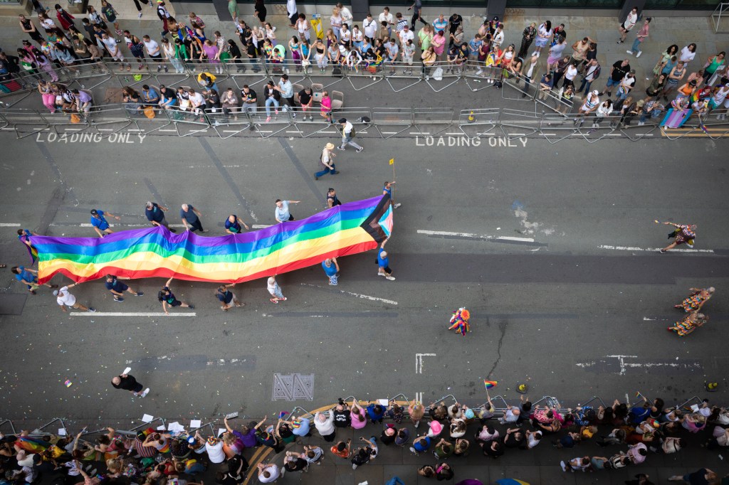 A bird's eye view of a Pride flag being flown along a parade route in Manchester.