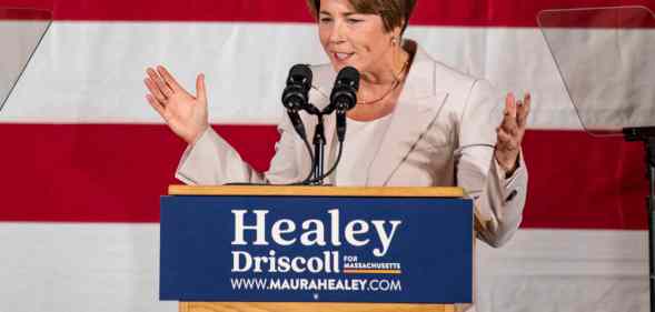 A photo of Democrat Maura Healey standing in front of the American flag as she talks into a microphone during her acceptance speech