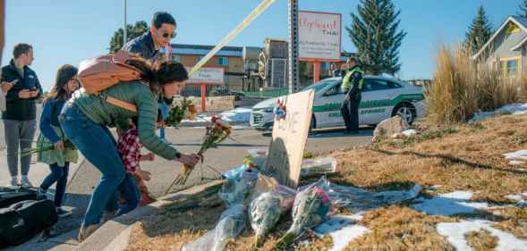Kara and CF Too and her children place flowers at the police tape for a growing memorial related to the shooting inside Club Q.
