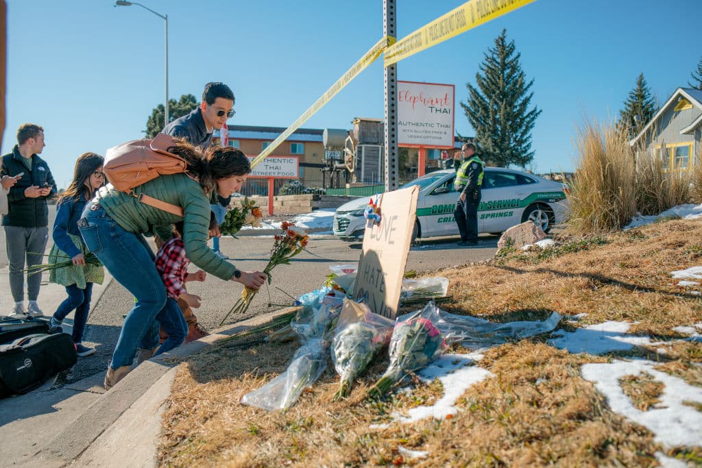 Kara and CF Too and her children place flowers at the police tape for a growing memorial related to the shooting inside Club Q.