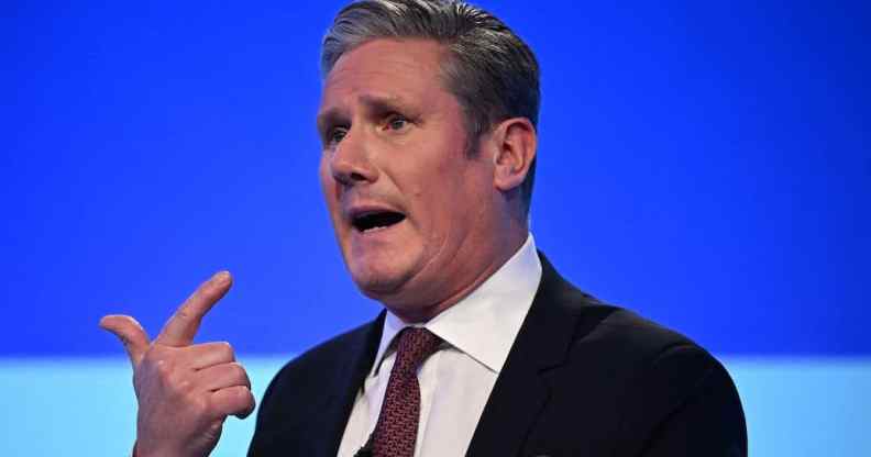 A screenshot of Labour leader Keir Starmer standing in front of a blue background and talking at a political conference