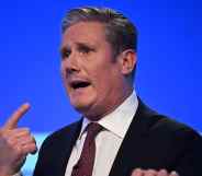 A screenshot of Labour leader Keir Starmer standing in front of a blue background and talking at a political conference