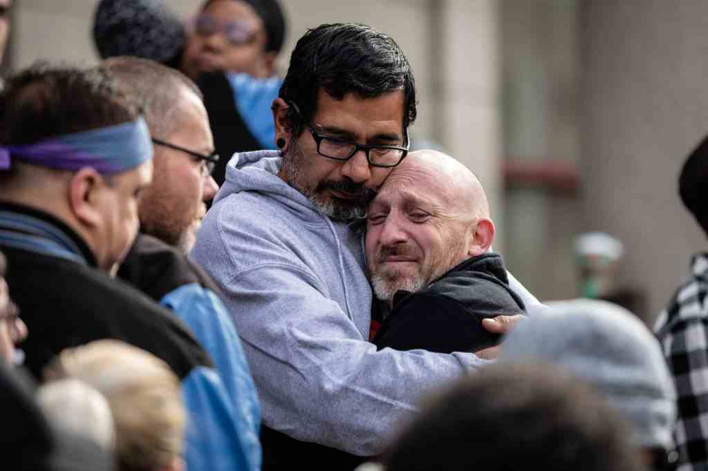 Club Q co-owner Nic Grzecka is embraced by mourners outside of the Colorado Springs City Hall.