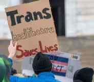 A trans rights protester holds a sign that reads: "Trans healthcare saves lives."