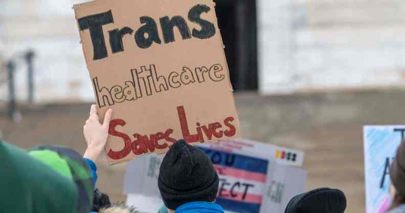 A trans rights protester holds a sign that reads: "Trans healthcare saves lives."