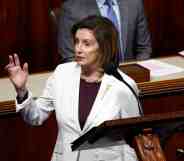 A photo of House Speaker Nancy Pelosi wearing a white suit jacket speaks behind a podium