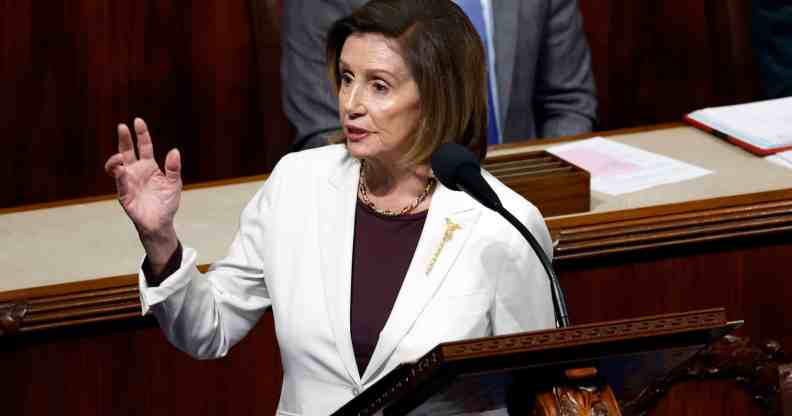 A photo of House Speaker Nancy Pelosi wearing a white suit jacket speaks behind a podium