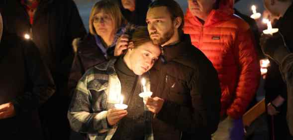 People hold a vigil at a makeshift memorial near the Club Q nightclub on November 20, 2022.