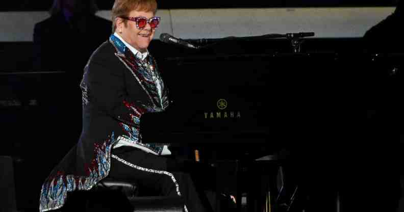 Elton John sitting at a piano in a sparkly blazer