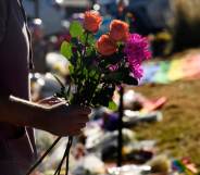 A closeup of a mourner's arm holding flowers to leave at the memorial for the victims of the Club Q shooting in Colorado Springs