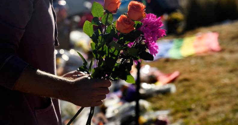 A closeup of a mourner's arm holding flowers to leave at the memorial for the victims of the Club Q shooting in Colorado Springs