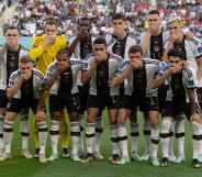German football team members pose with their hands covering their mouths as they line up for the team photo ahead of the FIFA World Cup Qatar match between Germany and Japan