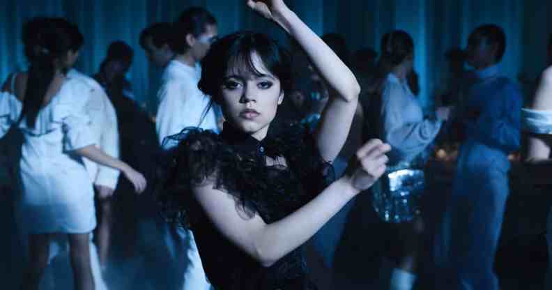 A still from Netflix's Wednesday series showing actor Jenna Ortega as Wednesday Addams dressed in a black dress and holding a dance pose