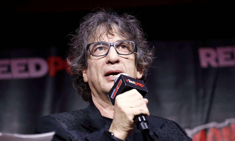 The Sandman creator Neil Gaiman speaks into a microphone at New York Comic Con 2022