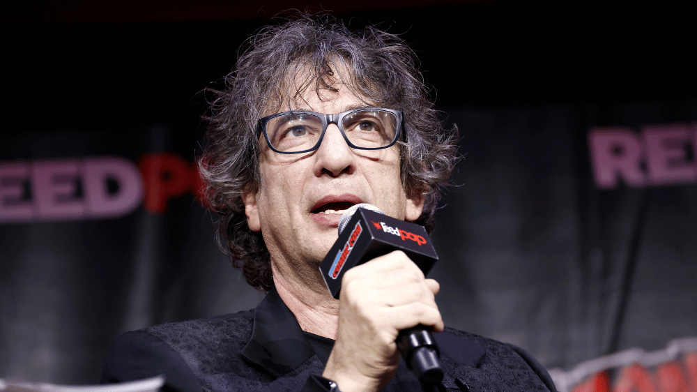 The Sandman creator Neil Gaiman speaks into a microphone at New York Comic Con 2022
