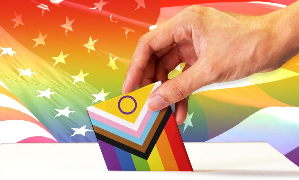 A Progress Pride flag being pushed into a ballot box with the US flag in the background