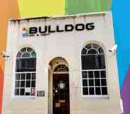 A small white building with Bulldog writte above the door. The picture has been cut out and placed on a rainbow background