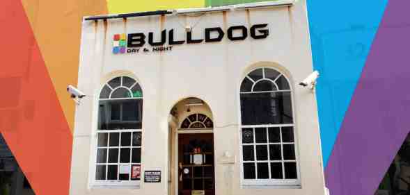 A small white building with Bulldog writte above the door. The picture has been cut out and placed on a rainbow background