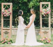 A same-sex couple gets married outside in white dresses