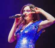 Sophie Ellis-Bextor singing into a microphone while doing a peace sign